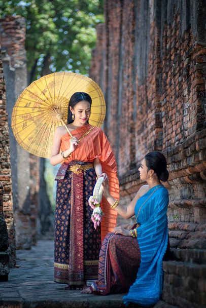 Pretty Asian Thai women with beautiful garland in here hand and wearing traditional Thai dress costume according Thai culture at the ancient temple Ayutthaya, Thailand - Photo, image