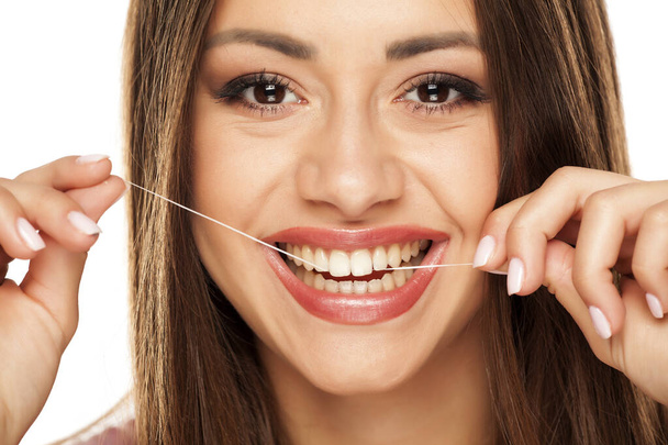 nuori kaunis nainen puhdistaa hampaansa hammaslangalla
 - Valokuva, kuva
