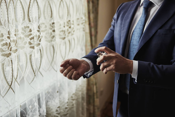 Handsome guy is choosing perfumes, Elegant man in suit using cologne,groom getting ready in the morning before wedding ceremony. Men Fashion - Photo, Image