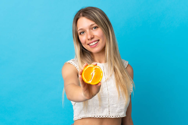 fiatal szőke nő elszigetelt lila háttér kezében egy narancs - Fotó, kép