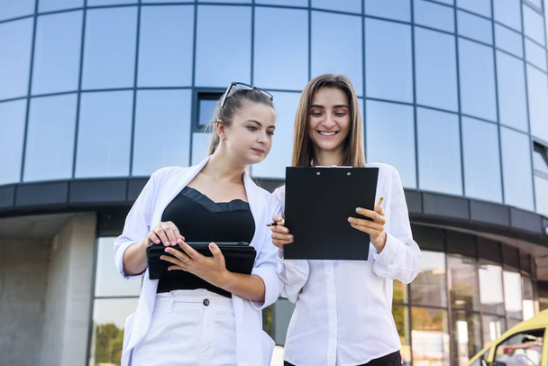 Business colleagues standing before big office center with tablet and clipboard  - Fotó, kép
