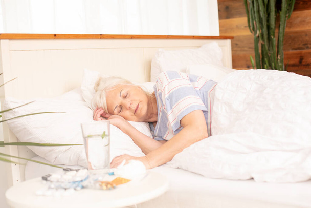 Seasonal flu. Sick senior woman with fever sleeping in bed, at home. - Φωτογραφία, εικόνα