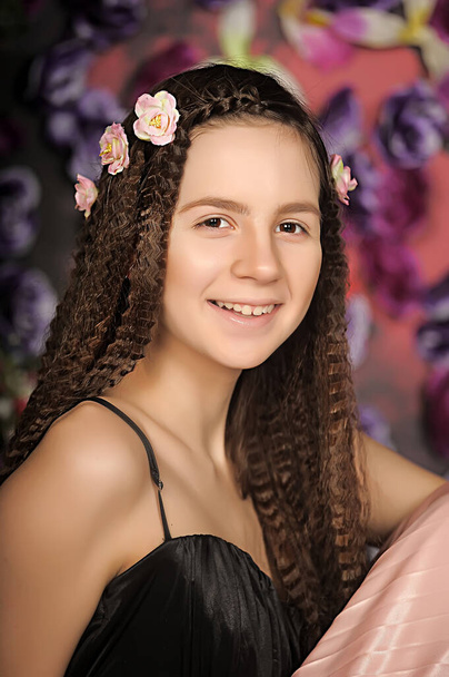 dziewczyna nastolatek brunetka portret z róże w fryzurę na kwiatowym tle - Zdjęcie, obraz