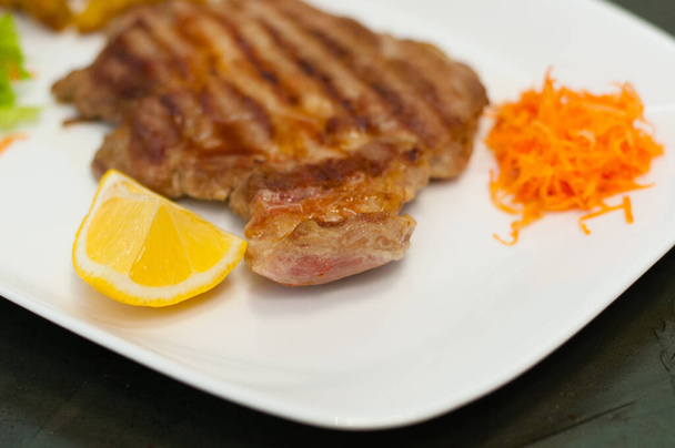 Bistecca di carne alla griglia succosa e deliziosa con limone, lattuga di carote e patate
. - Foto, immagini