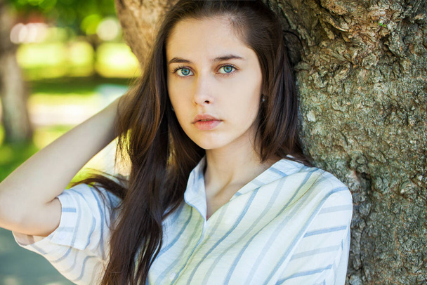 Close up portrait of a young beautiful brunette  girl in summer park - Zdjęcie, obraz