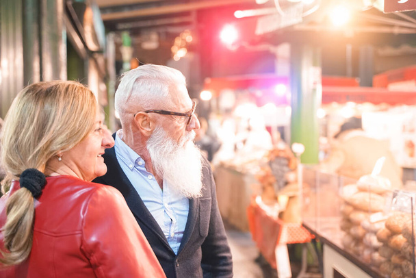 Подружжя пенсіонерів дивиться на сховища харчів на ринку вуличної їжі - Дружина з чоловіком роблять екскурсію по місту в Лондоні - подорожують і радіють стареньким способом життя - зосереджуються на обличчі чоловіка - Фото, зображення