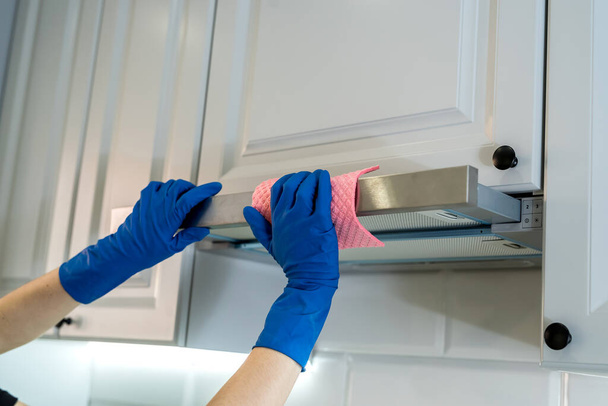 γυναικείο χέρι σε προστατευτική απορροφητήρα κλίνει με κουρέλι στην κουζίνα - Φωτογραφία, εικόνα