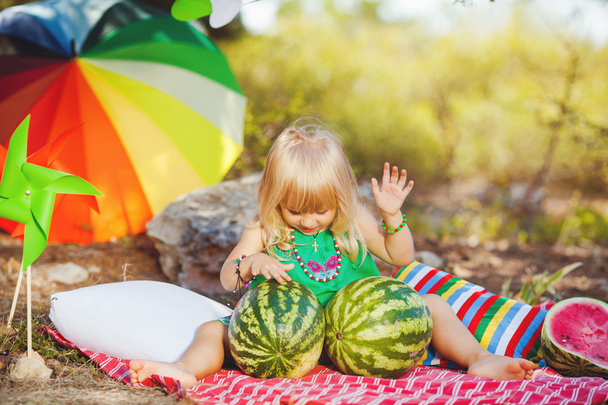 Cute little girl playing with watermelons in summer park outdoors - Foto, Imagem
