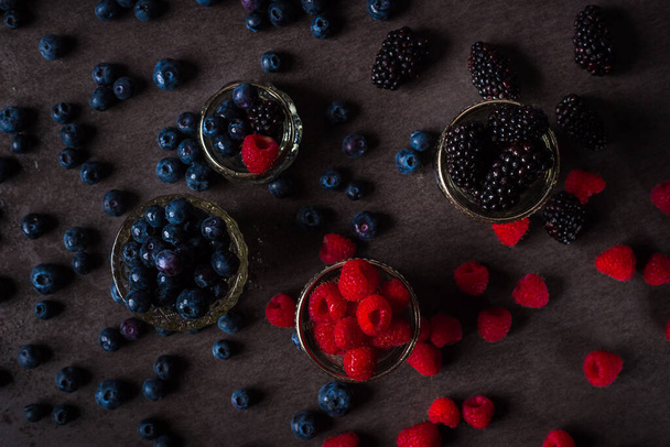 close up of wet raspberry, blueberries and blackberries in small bowls - Fotoğraf, Görsel