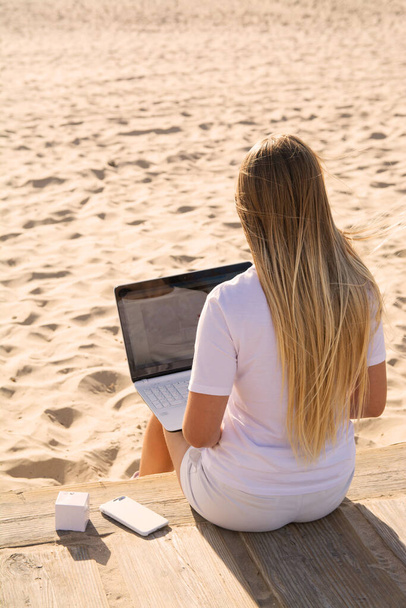 Woman Working at Computer on the Beach.Young pretty woman with white laptop on the summer beach. - Valokuva, kuva