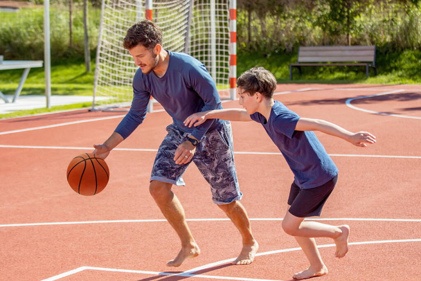 Father and son playing basketball barefoot on a playground - Φωτογραφία, εικόνα