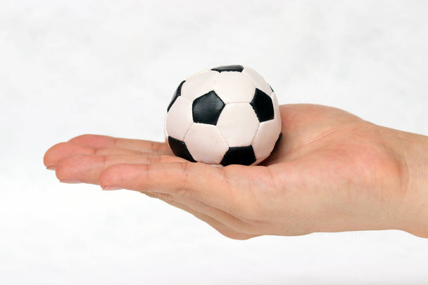 Μίνι μπάλα ποδοσφαίρου στο χέρι σε λευκό φόντο. Έννοια του αθλητισμού ή το παιχνίδι στη λαβή. - Φωτογραφία, εικόνα