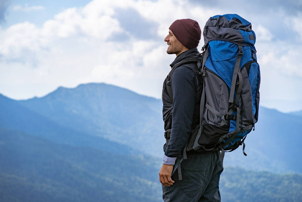 山の上に立っているキャンプバックパックを持つ男性 - 写真・画像