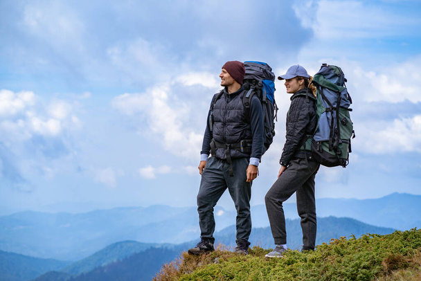 O homem e uma mulher com mochilas em pé no fundo da paisagem da montanha
 - Foto, Imagem