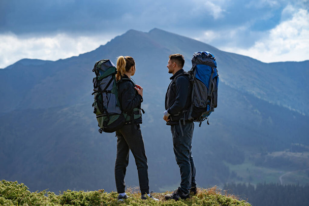 Das Paar mit dem Rucksack steht vor dem Hintergrund der Berglandschaft - Foto, Bild