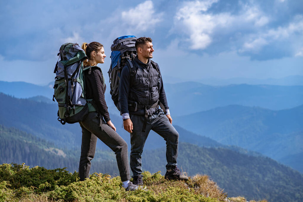 The couple with backpacks enjoying on a beautiful mountain landscape background - Foto, Imagen