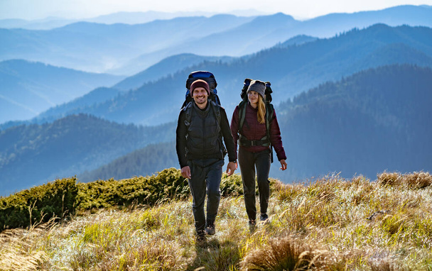 山に歩いてバックパックを持つ幸せなカップル - 写真・画像