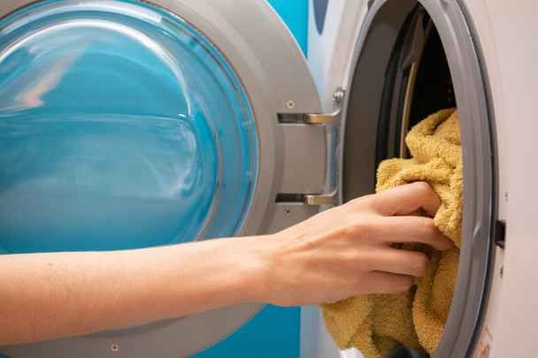 Main enlève la lessive de la machine à laver. Chargement de la blanchisserie dans la machine à laver
. - Photo, image