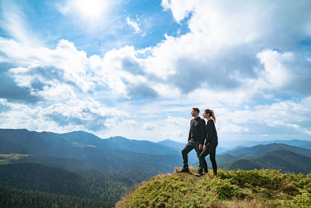 Το ευτυχισμένο ζευγάρι που στέκεται στο βουνό με ένα γραφικό σύννεφο - Φωτογραφία, εικόνα