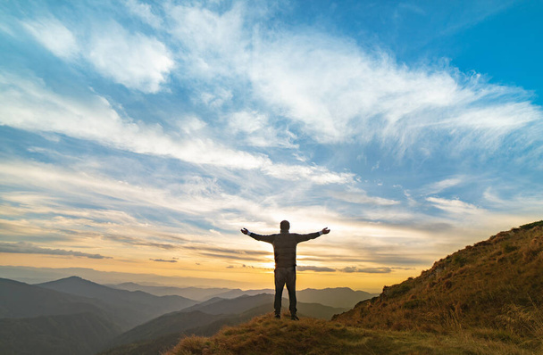 Щасливий чоловік стоїть на скелі з мальовничим заходом сонця
 - Фото, зображення