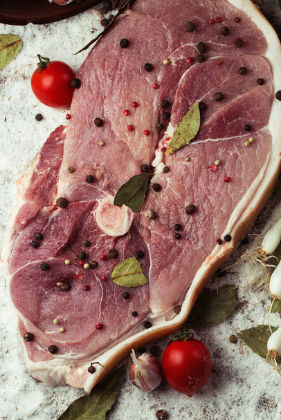 Slices of raw pork knuckle on wooden background. Raw pork meat isolated with vegetables. Advertising for meat shop and farm. Various kinds of meat and ready to cook concept. Top view. - Foto, Imagem
