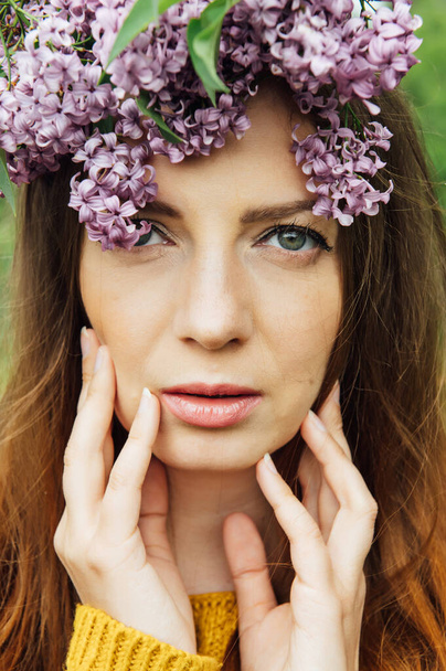 Beautiful woman with lilac flower wreath. Girl in a wreath of lilac in the spring. - Фото, зображення