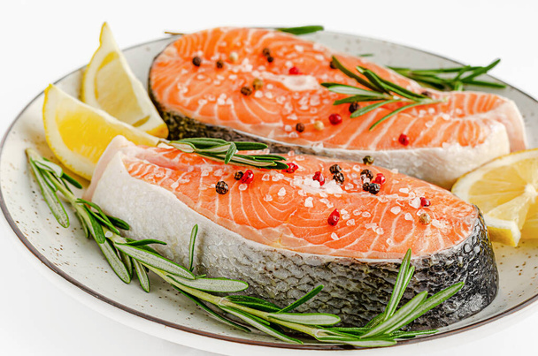 Raw salmon fish steaks with pepper, sea salt, rosemary and lemon on white. Top view, keto diet and healthy eating concept. - Photo, Image