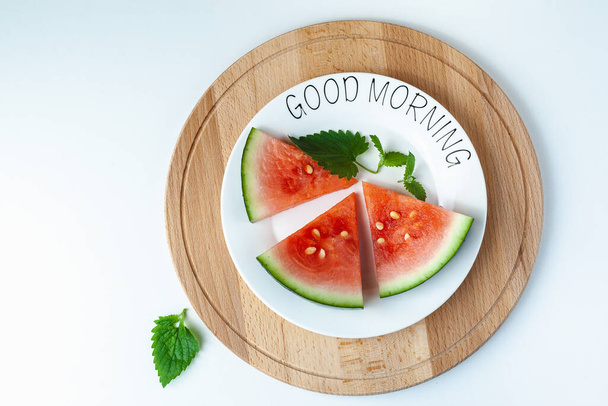 Wassermelone liegt auf einem Teller mit der Aufschrift Guten Morgen, auf einem Holztablett. Super Essen für Vegetarier. Geeignet für Banner, Plakate, Webseiten, Werbung. - Foto, Bild