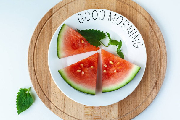 Watermelon lies on a plate with lettering Good morning, on a wooden tray. Super food for vegetarians. Suitable for banner, poster, web site, advertisement. - Foto, imagen