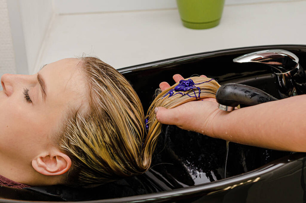 Peluquero aplicando champú púrpura para colorear después de teñir el cabello
. - Foto, Imagen