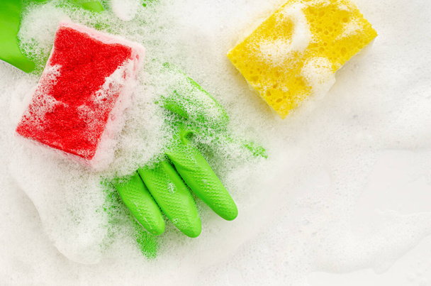 Koruyucu yeşil eldivenlerin ve sabunlu arka planda süngerin üst görüntüsü. Ev işi konsepti. Boşluğu kopyala, üst görünüm - Fotoğraf, Görsel