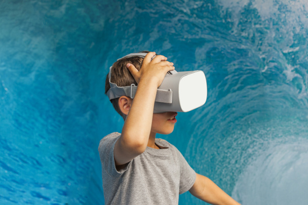 映画やゲームを見て仮想現実のゴーグルを身に着けて幸せな男の子。VRメガネで見ている笑顔の男の子。仮想現実を体験する面白い子供。3D技術 - 写真・画像