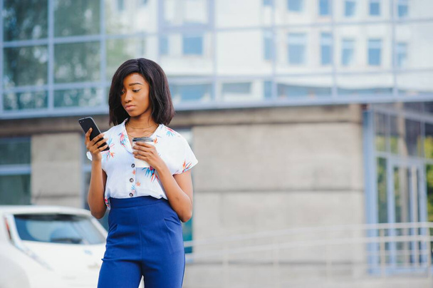 African American female entrepreneur using online banking for transferring money distantly via smartphone. Confident businesswoman texting email letter on cellphone using internet - Foto, imagen