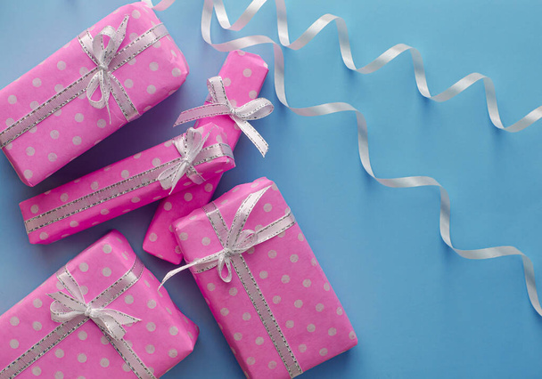 Cadeau of cadeau roze doosjes met lint op pastelblauwe achtergrond. Platte lay compositie voor feestdagen groeten. Kopieerruimte - Foto, afbeelding