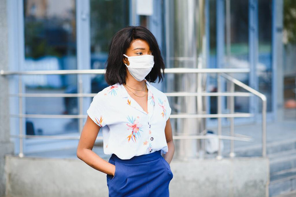 African American businesswoman wearing protective mask on her face in the city. The concept of visiting work during a pandemic - Foto, imagen