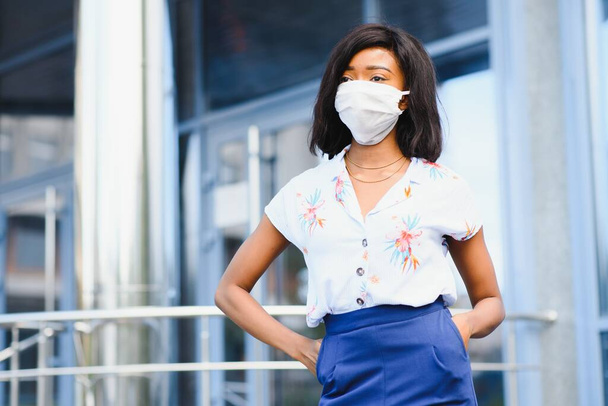 African american young volunteer woman wearing face mask outdoors. Coronavirus quarantine and global pandemic. - Фото, изображение