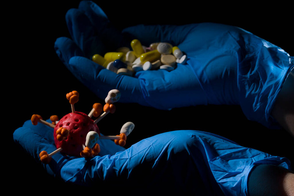 Doctors hands filled with pills and coronavirus molecule on black background . Close up  - Photo, Image