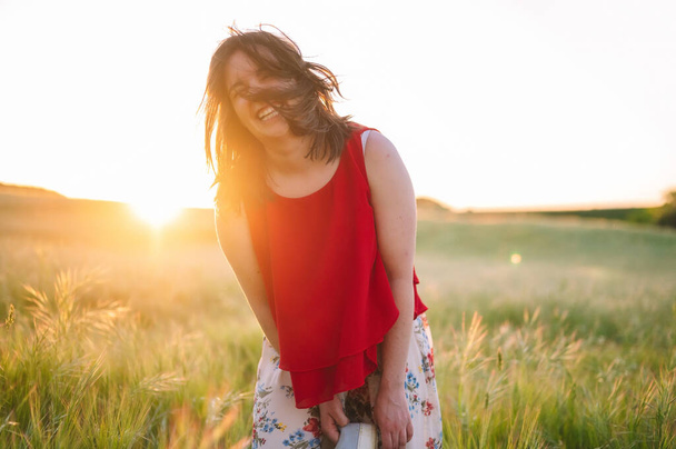 Cute girl in red dress, laughing with joy outdoors in the springtime sunset. - Foto, Imagem