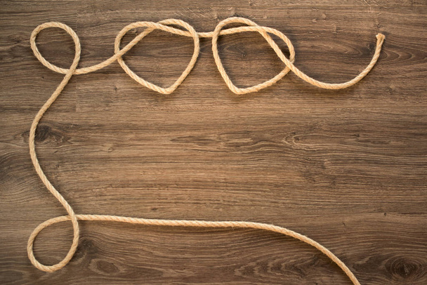 Две формы сердца на старой деревянной стене из вязаной веревки
 - Фото, изображение