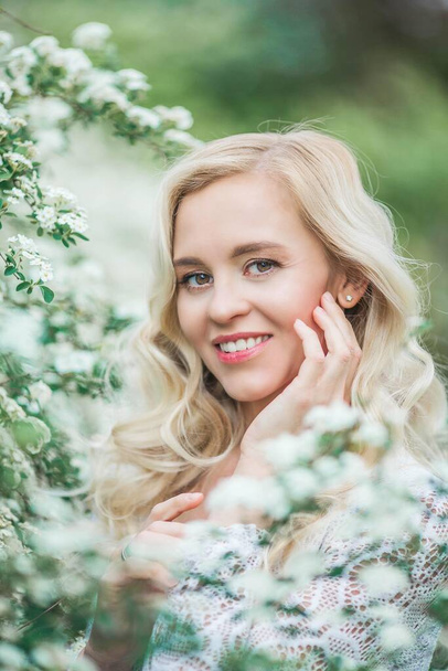 Portrait of a beautiful young blonde in white blossoms. Spring portrait of a young woman. Spring. - Foto, immagini