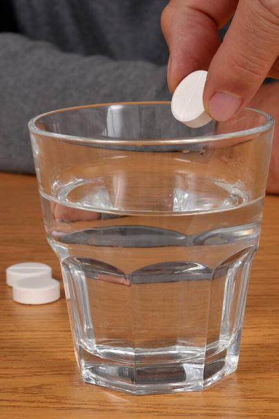 Brause-Aspirin-Tablette in ein Glas Wasser geben  - Foto, Bild