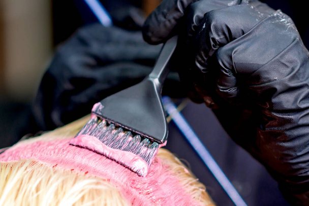 Barvící vlasy ženy. Detailní kadeřnické ruce barvení ženské vlasy v růžové barvě. - Fotografie, Obrázek