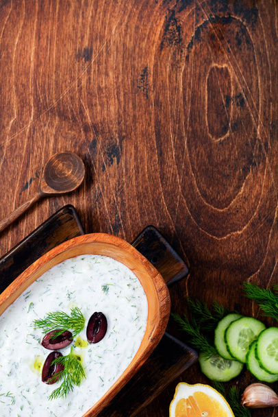 Traditional Greek sauce Tzatziki in olive wooden bowl on old rustic background. Top view. - Valokuva, kuva