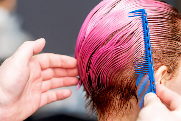 Ruce kadeřnice jsou česání růžové vlasy ženy, zblízka. - Fotografie, Obrázek