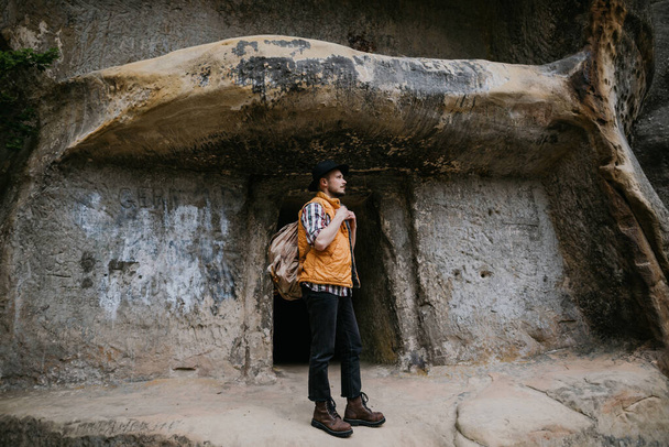 A male tourist stands at the entrance to the cave city - Fotó, kép