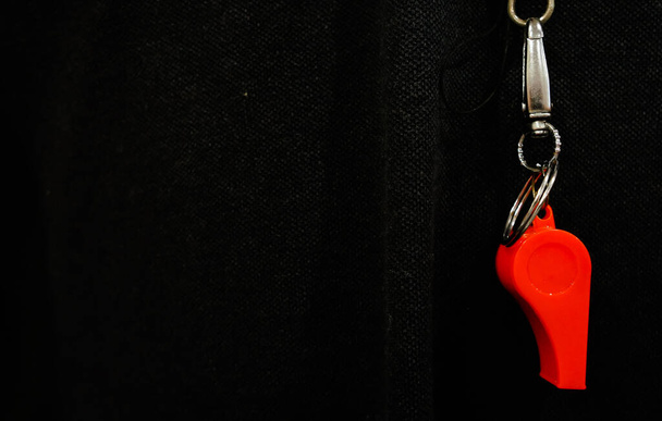 красный тренерский свисток висит на шее на серой футболке
 - Фото, изображение