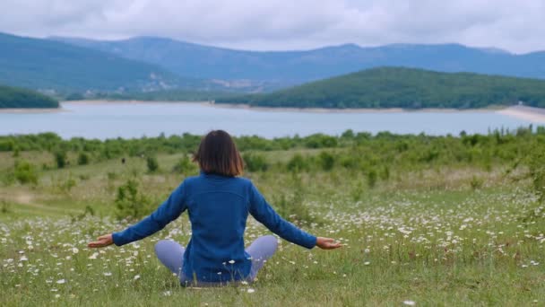 Mooie vrije en wilde vrouw zittend in meditatie poseren op het madeliefje veld lotuspositie geneeskunde yoga asana evenwicht, kundalini energie, elke dag routine, oefenen goed voor de gezondheid van de vrouw mindfulness - Video