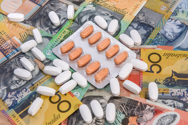 Medicina e costo della salute. Compresse sparse su banconote colorate in dollari australiani da vicino - Foto, immagini