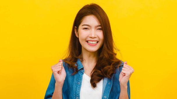 Portret młodej Azjatki o pozytywnym wyrazie twarzy, radosnej i ekscytującej, ubranej w luźne ubrania i patrzącej w kamerę na żółtym tle. Szczęśliwa, urocza kobieta cieszy się sukcesem.. - Zdjęcie, obraz