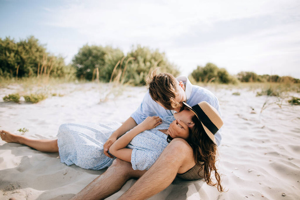 Young couple kissing on the sea beach at sunrise. The concept of love and summer vacation - Foto, imagen